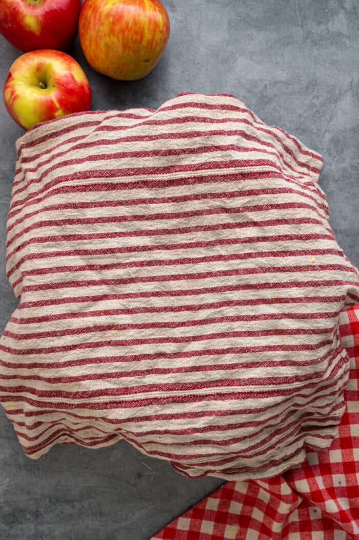 Each bite of these Applesauce Muffins is incredibly moist and infused with warm apple flavor. They look like something straight from a bakery! A towel over a mixing bowl