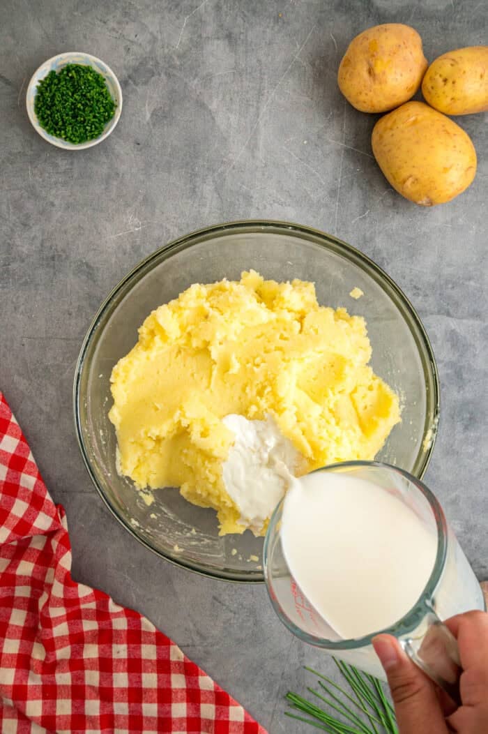 Pouring heavy cream into mashed potatoes