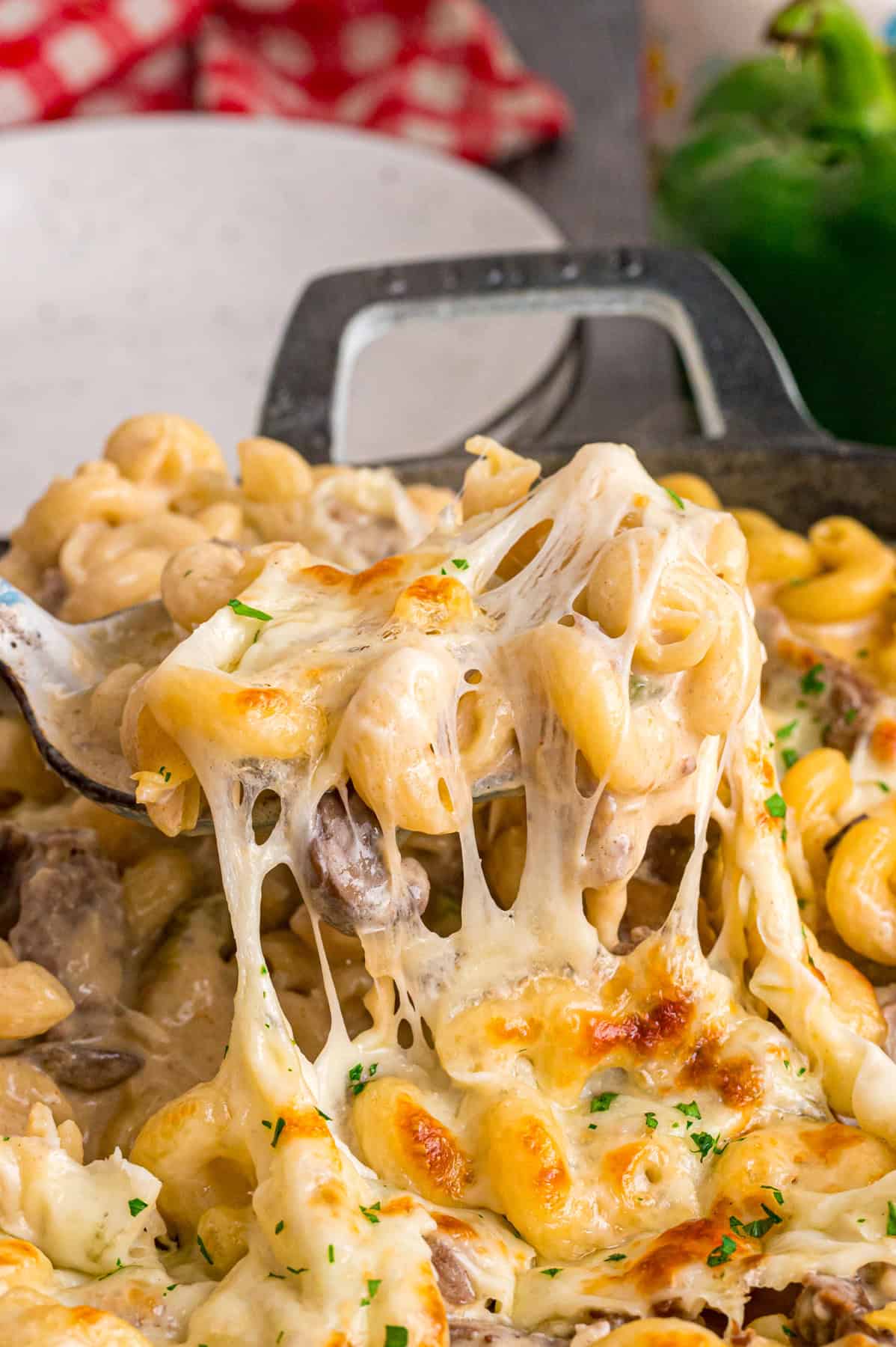 Loaded with sliced ribeye, peppers, onions, mushrooms, and lots of cheese, this Philly Cheesesteak Pasta is an easy one-pan dinner. A spoon serving Philly cheesesteak pasta