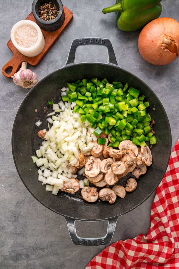Loaded with sliced ribeye, peppers, onions, mushrooms, and lots of cheese, this Philly Cheesesteak Pasta is an easy one-pan dinner. Onions, green peppers, and mushrooms in a skillet