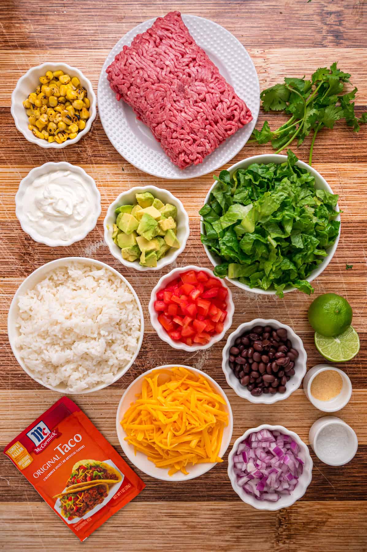 Elevate Taco Tuesday with this easy Taco Bowl recipe. With seasoned taco meat, rice and cilantro lime crema, it's an easy weeknight dinner. Overhead view of ingredients needed to make taco bowls