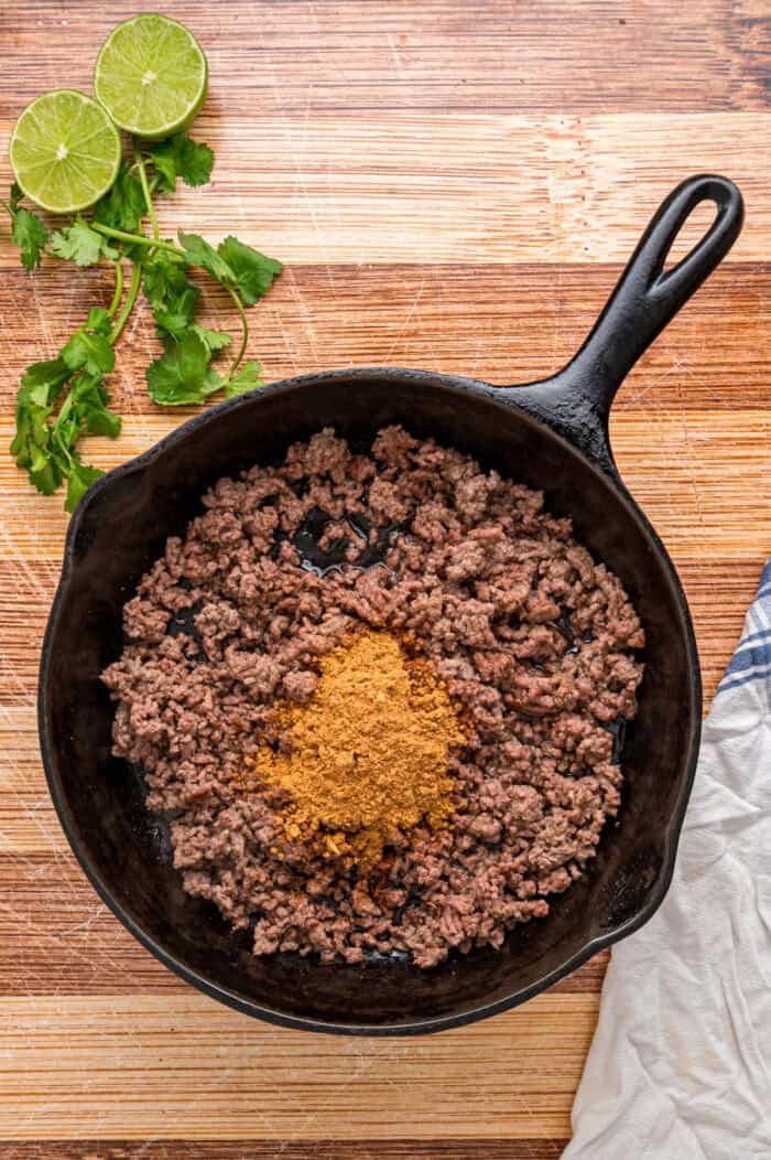 Elevate Taco Tuesday with this easy Taco Bowl recipe. With seasoned taco meat, rice and cilantro lime crema, it's an easy weeknight dinner. Taco seasoning added to ground beef in a skillet