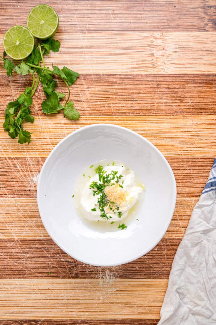 Elevate Taco Tuesday with this easy Taco Bowl recipe. With seasoned taco meat, rice and cilantro lime crema, it's an easy weeknight dinner. Cilantro, lime zest, and sour cream in a bowl