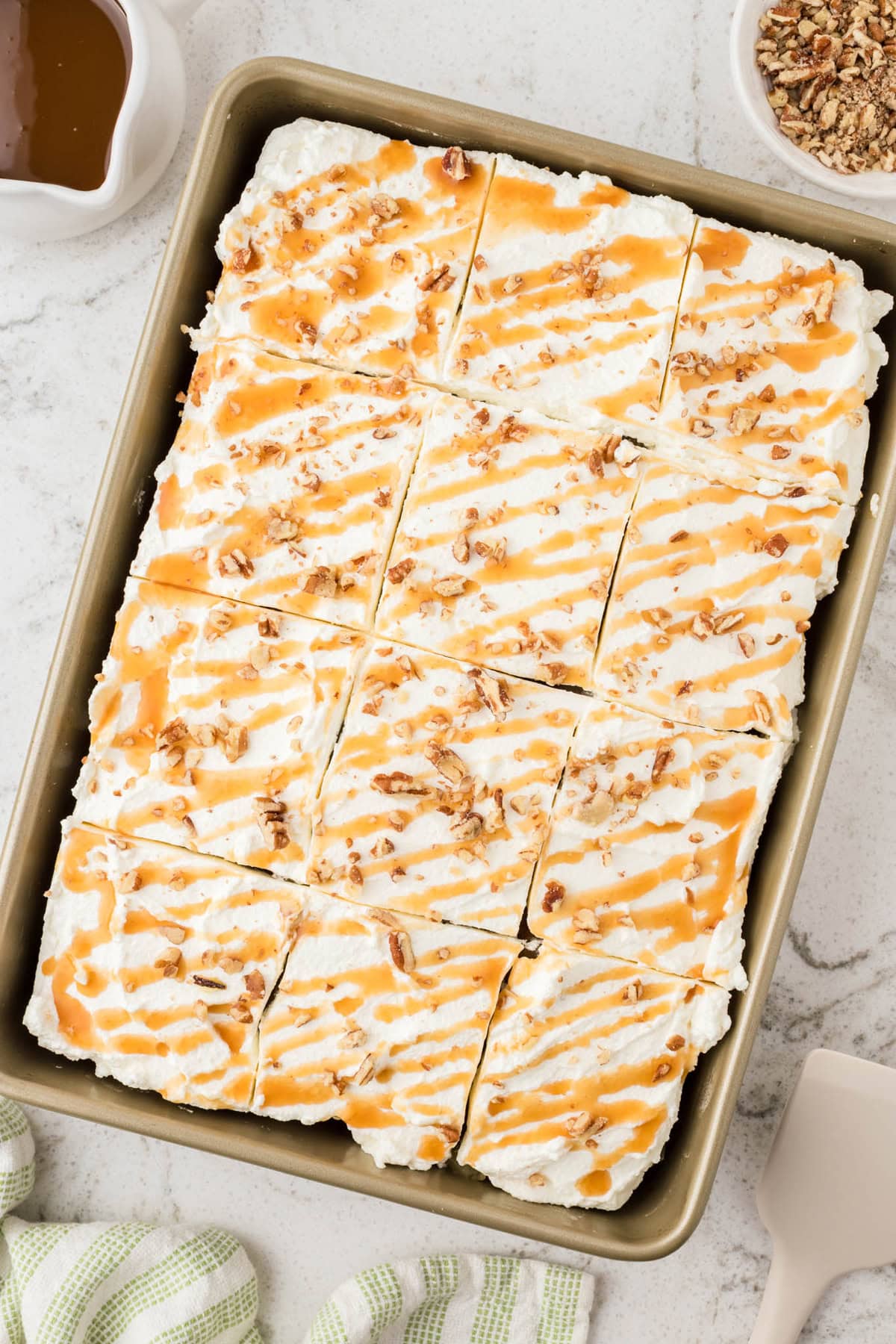 Vanilla cake is drizzled with caramel sauce and then topped with apple pie filling and whipped cream in this Caramel Apple Poke Cake recipe. Overhead view of a caramel apple poke cake