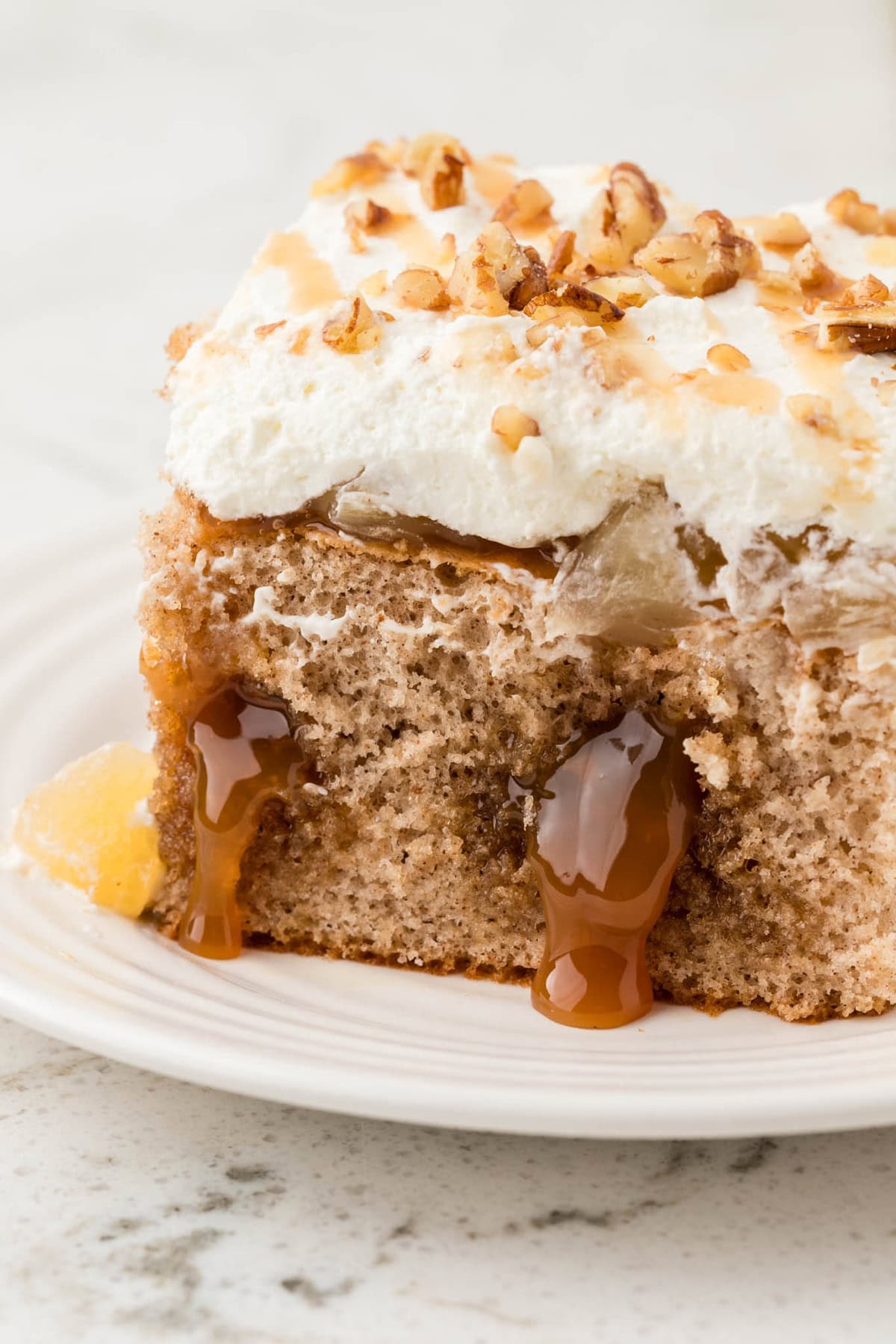 A slice of caramel apple poke cake on a white plate