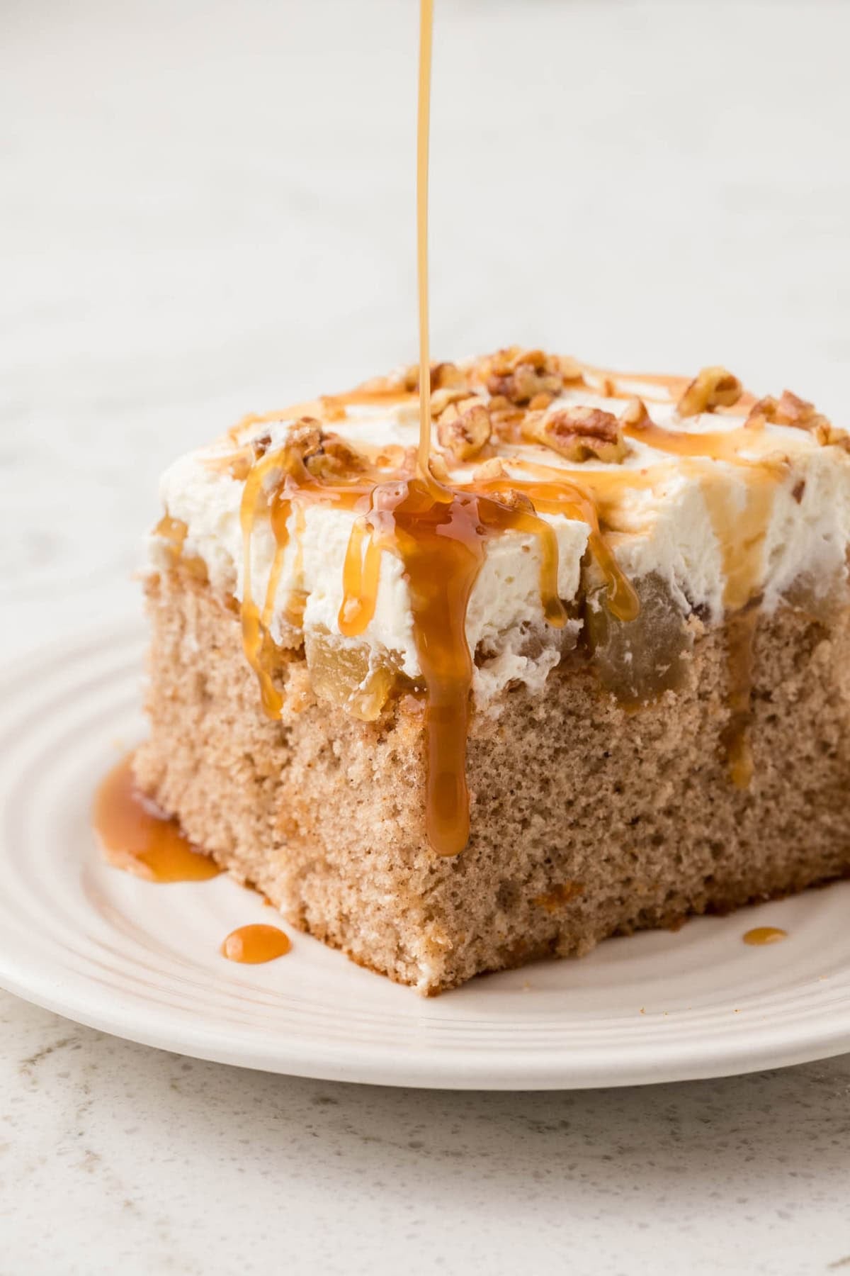 Vanilla cake is drizzled with caramel sauce and then topped with apple pie filling and whipped cream in this Caramel Apple Poke Cake recipe. Drizzling caramel sauce over a slice of caramel apple poke cake