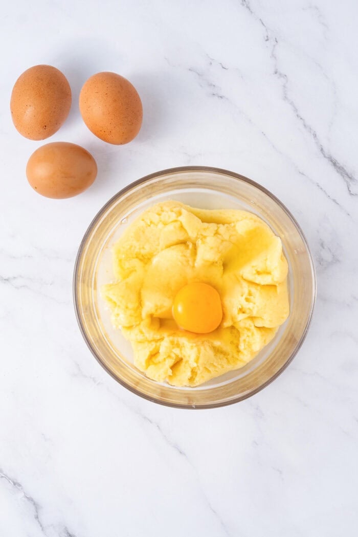 This festive Croquembouche features a stunning tower of cream puffs dipped in glossy amber caramel and sprinkled with shredded coconut. Egg added to panade