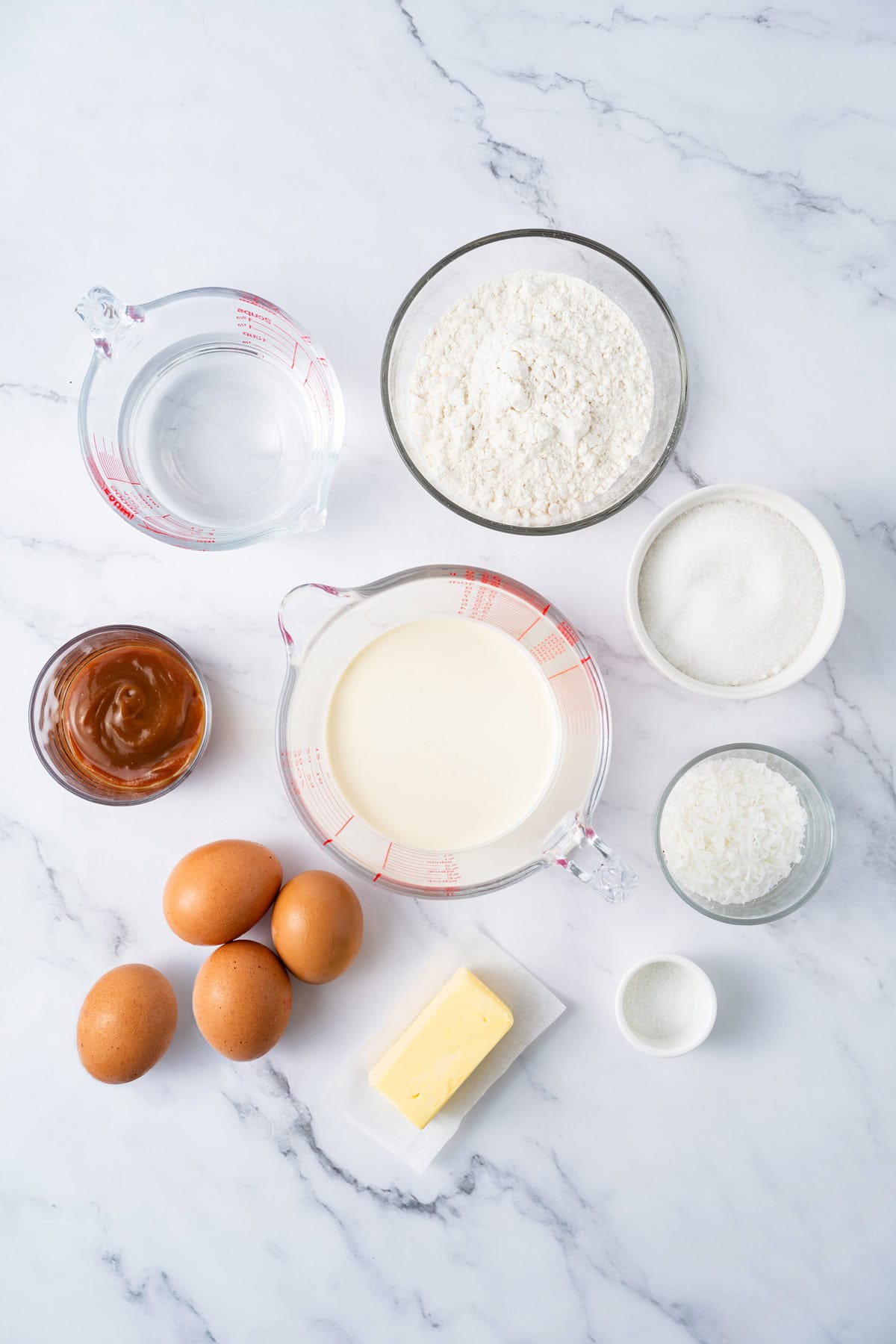 This festive Croquembouche features a stunning tower of cream puffs dipped in glossy amber caramel and sprinkled with shredded coconut. Overhead view of ingredients needed to make croquembouche