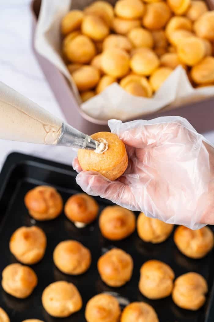This festive Croquembouche features a stunning tower of cream puffs dipped in glossy amber caramel and sprinkled with shredded coconut. Filling choux puffs with cream