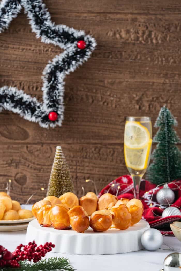 This festive Croquembouche features a stunning tower of cream puffs dipped in glossy amber caramel and sprinkled with shredded coconut. The first layer of a Croquembouche on a plate