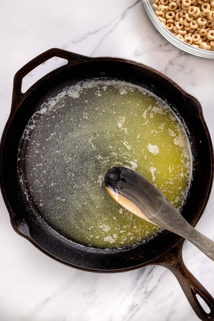 Hot Buttered Cheerios, aka Fried Cheerios, are a nostalgic snack featuring Cheerios toasted in butter and tossed with cinnamon sugar. Melted butter in a cast iron skillet
