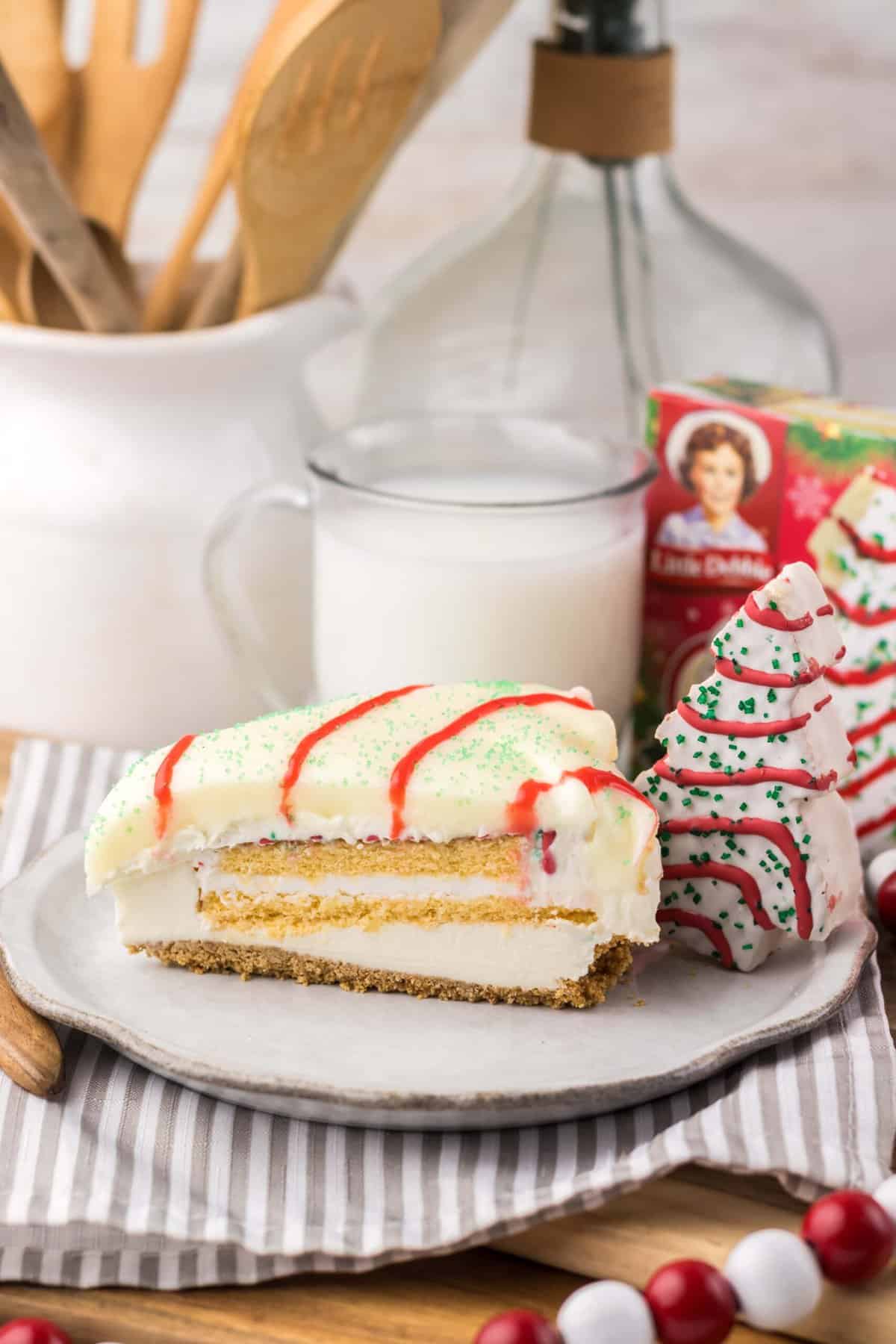 With no baking required, this Little Debbie Christmas Tree Cheesecake is a fun, festive, and nostalgic Christmas treat. A slice of Little Debbie Christmas Tree Cheesecake on a white plate
