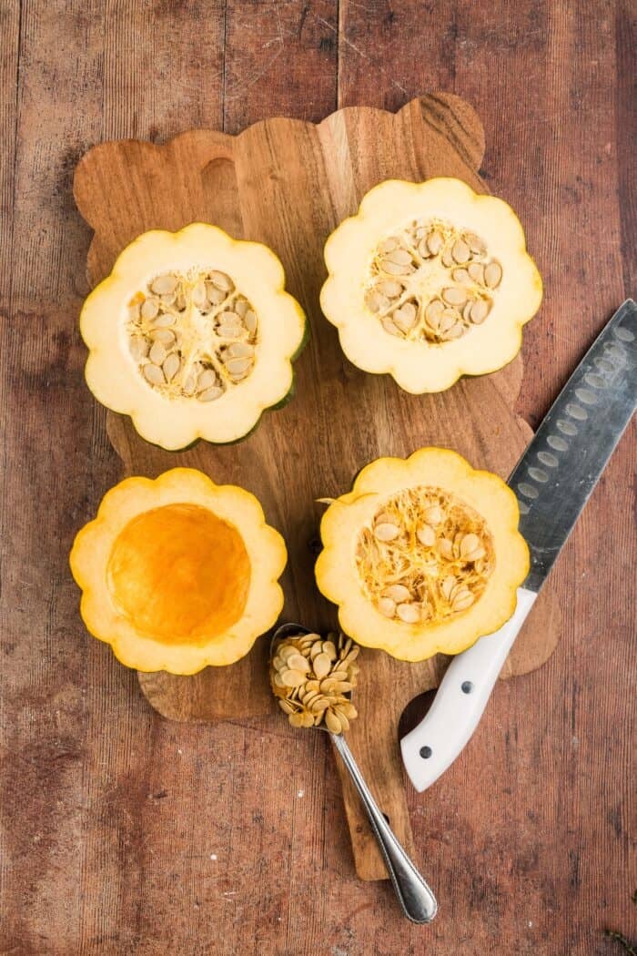Squash is coated in a sweet, savory, and buttery glaze that caramelizes in the oven in this Maple Butter Roasted Acorn Squash recipe. Two acorn squash cut in half, one with the seed scooped out