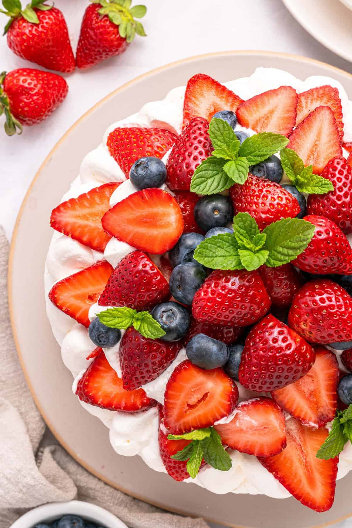 This Strawberry Meringue Cake is light, crisp, and creamy all at once with layers of meringue, fresh strawberries, and whipped cream. Overhead view of fruit on top of strawberry meringue cake