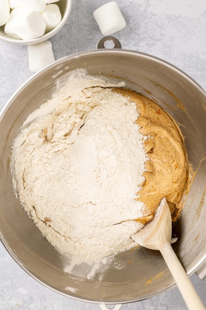 Combining wet and dry cookie dough ingredients.