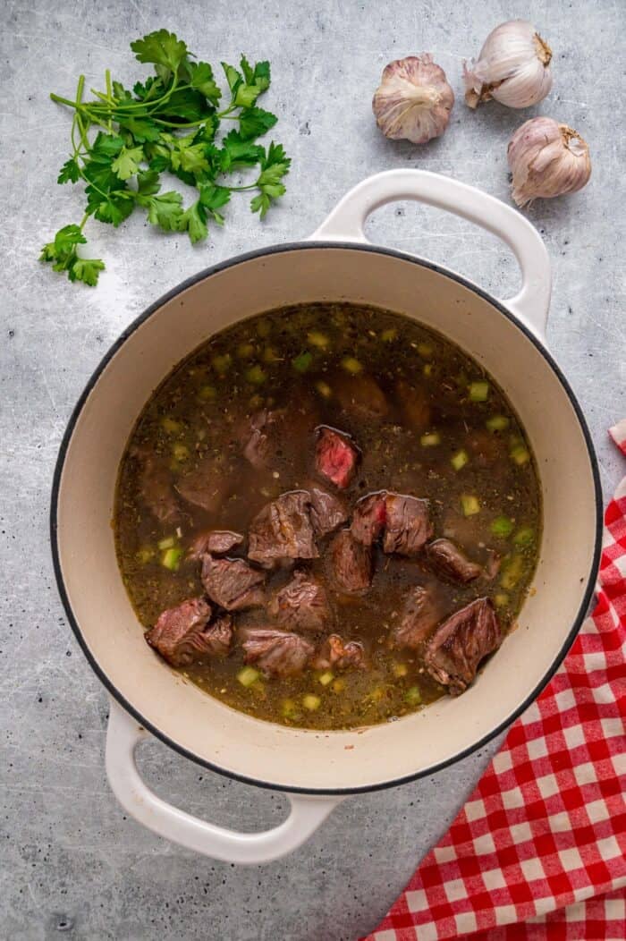 Tender chunks of beef are cooked in a rich, savory gravy and served over egg noodles in this easy Beef and Noodles recipe. Seared beef added to gravy in a Dutch oven
