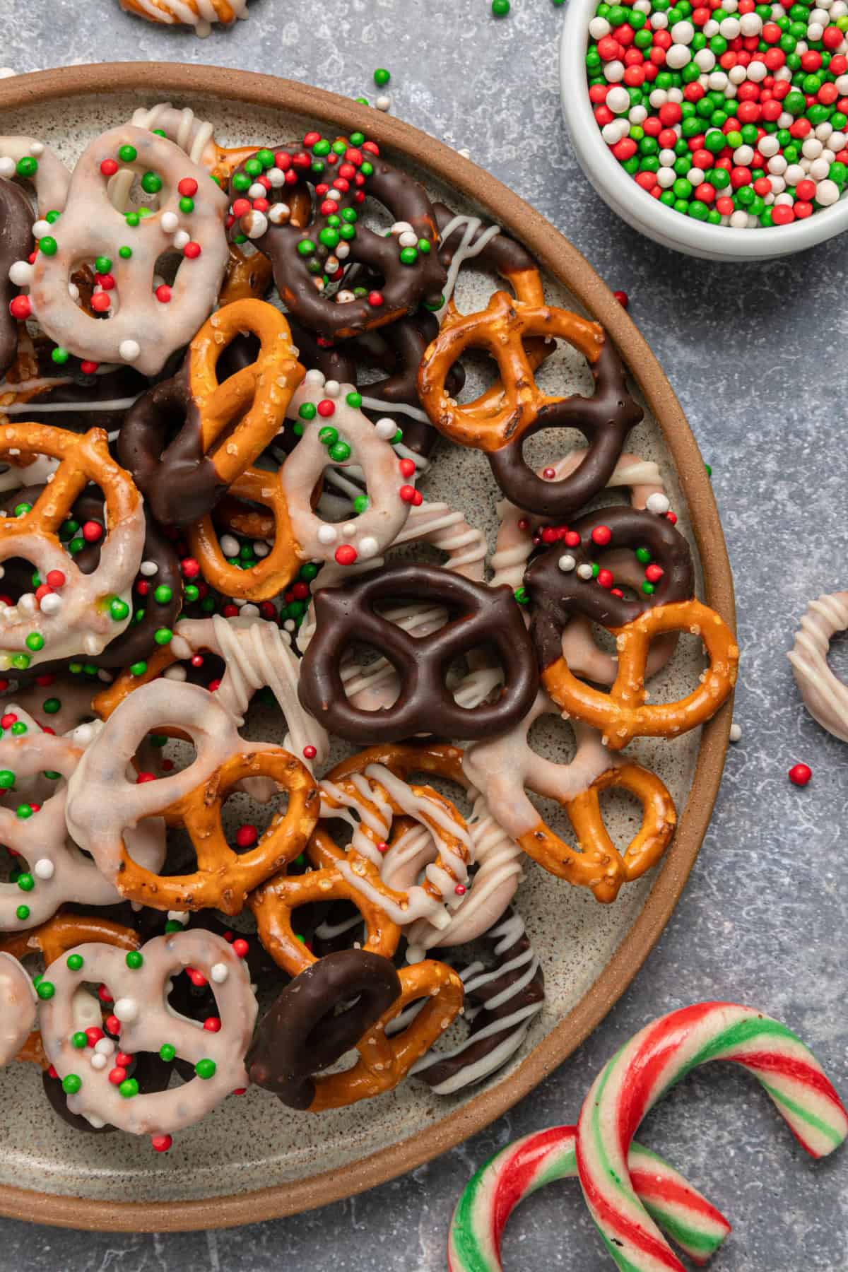 These Chocolate Covered Pretzels are made with pretzel twists coated in dark and white chocolate and decorated with sprinkles. various Chocolate Covered Pretzels on a plate