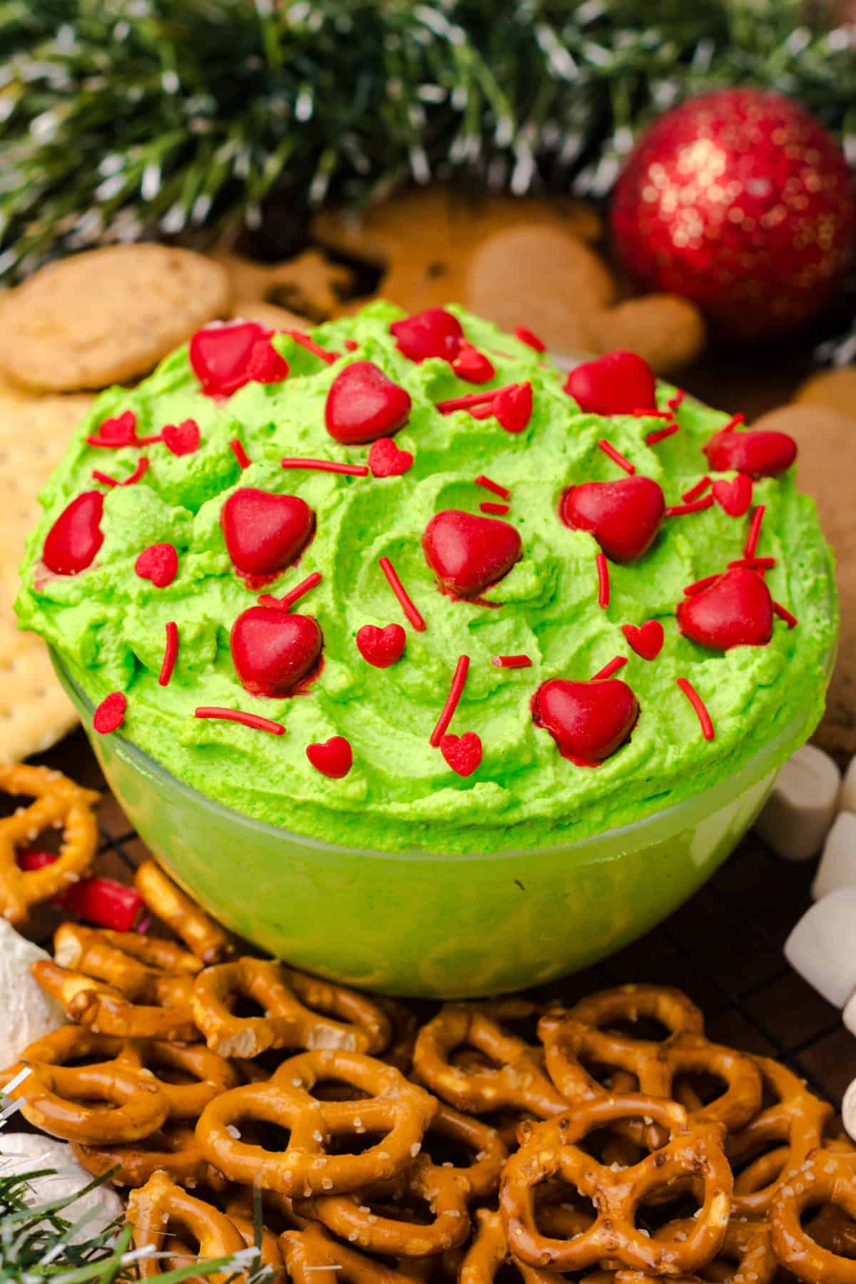 Grinch Dip in a bowl surrounded by snacks