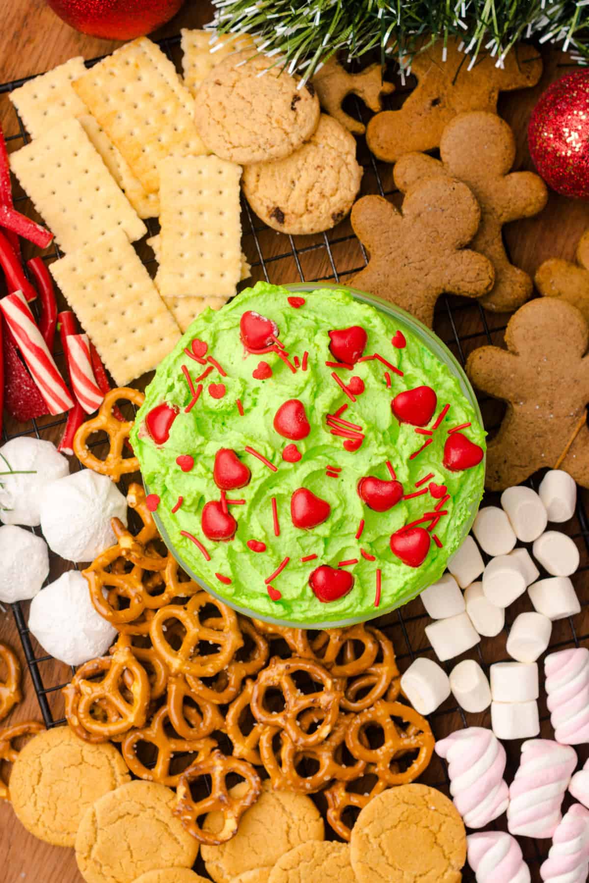 Grinch Dip in a bowl surrounded by assorted snacks