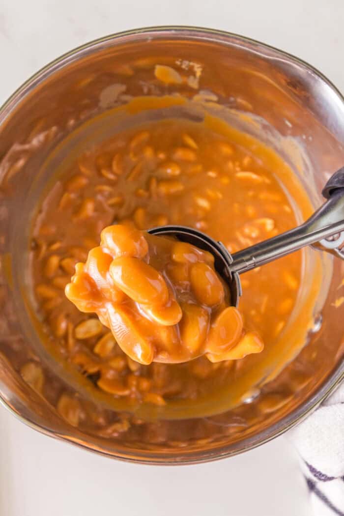 This Polar Bear Paws Candy recipe is a copycat version of See’s Candies that you can easily at home! measuring peanut candy mixture with a scoop