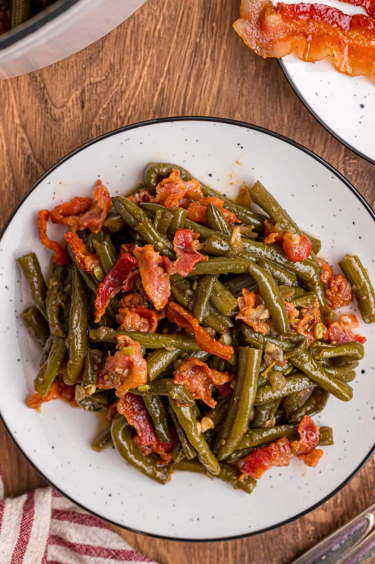 Fresh green beans are slow-cooked until tender with garlic, onion, bacon, and some Cajun seasoning in this Southern Green Beans recipe. Overhead view of a plate of Southern style green beans