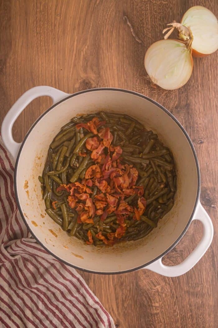 Fresh green beans are slow-cooked until tender with garlic, onion, bacon, and some Cajun seasoning in this Southern Green Beans recipe. Bacon added to a pot with cooked green beans