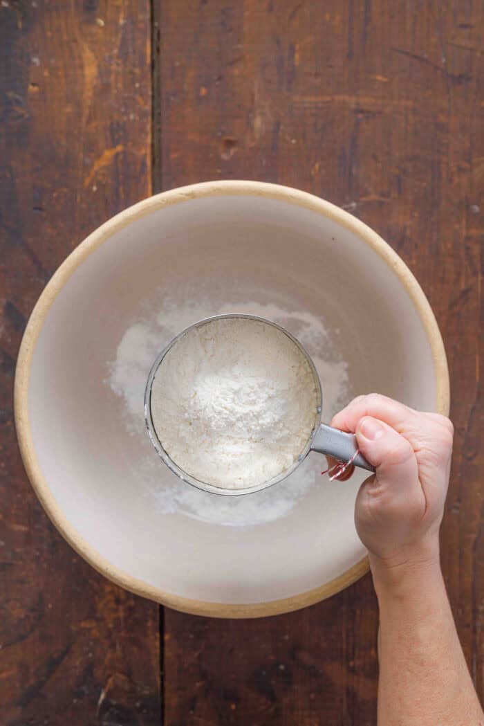 Adding flour to a mixing bowl