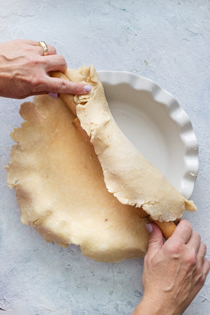 Unrolling pie crust over a pie plate