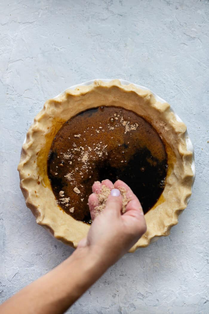 Sprinkling crumb topping over molasses pie filling