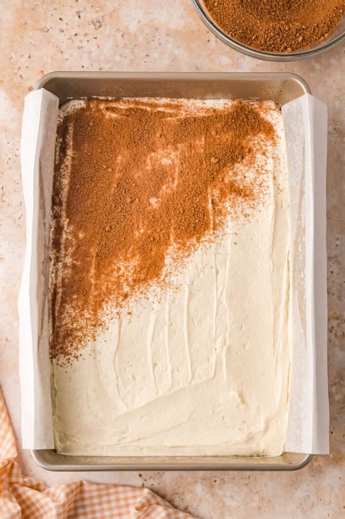 This Sour Cream Coffee Cake is soft and buttery with a generous cinnamon sugar ribbon baked through the middle & streusel topping. Sprinkling cinnamon sugar on top of coffee cake batter