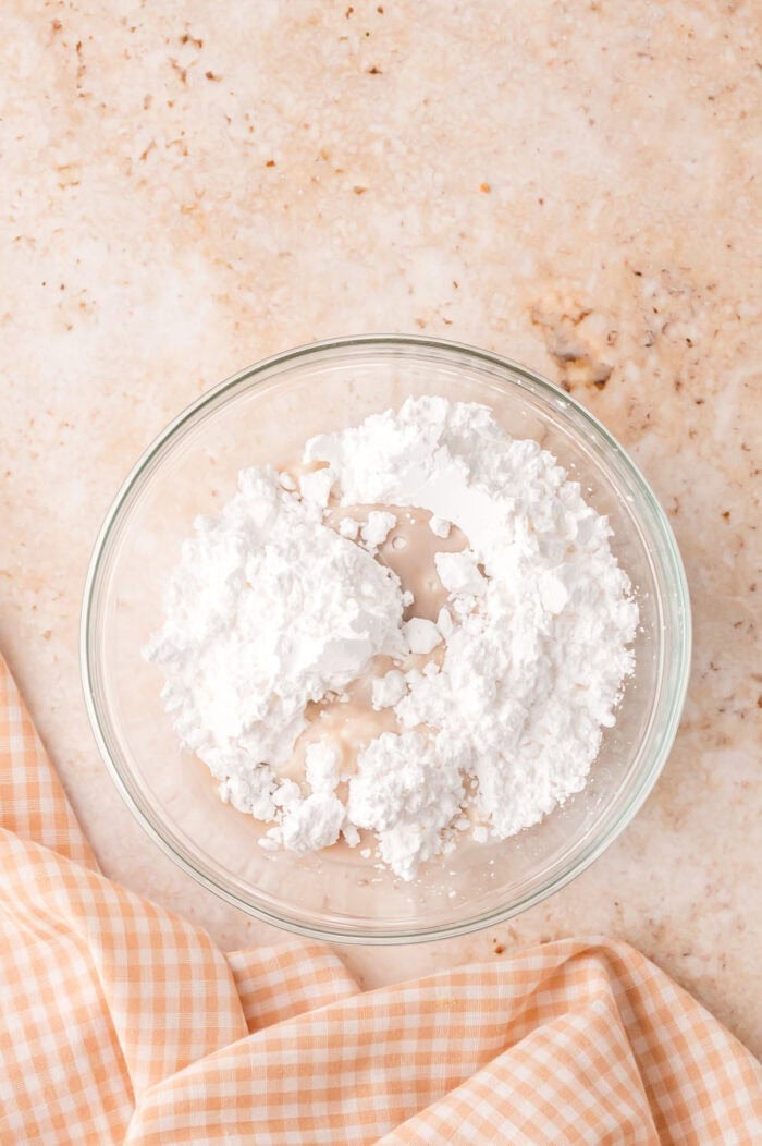 This Sour Cream Coffee Cake is soft and buttery with a generous cinnamon sugar ribbon baked through the middle & streusel topping. Powdered sugar, vanilla, and milk in a bowl.