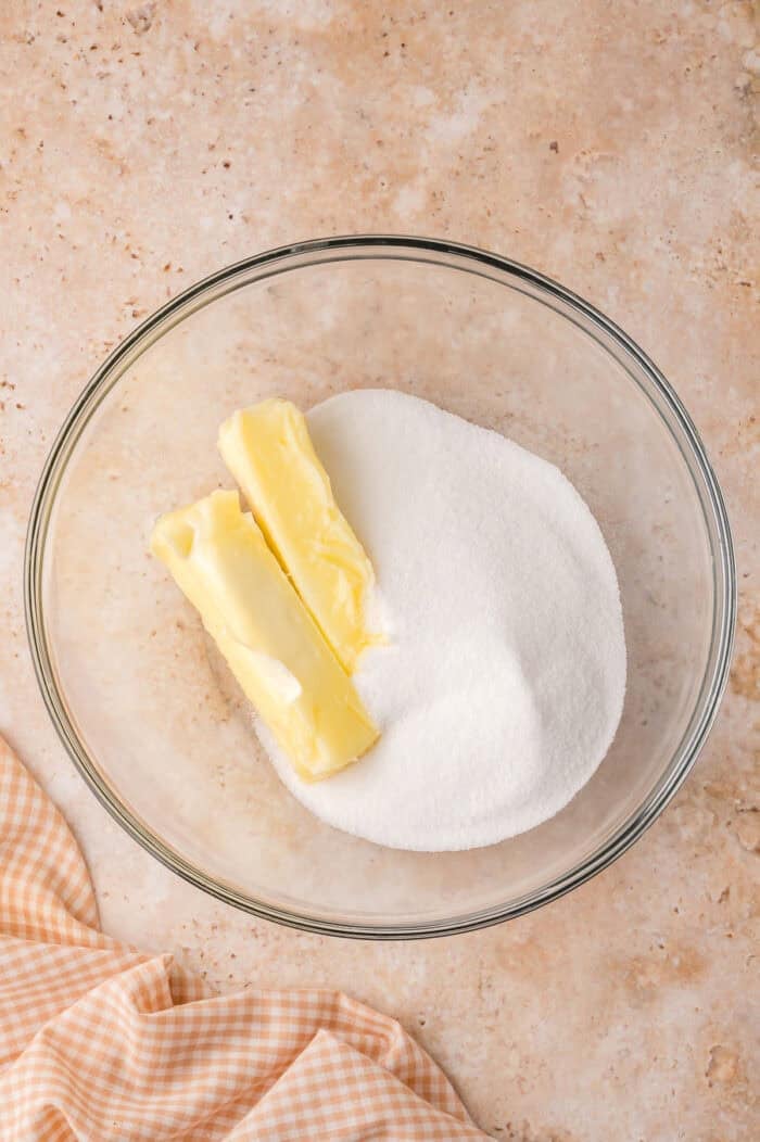 This Sour Cream Coffee Cake is soft and buttery with a generous cinnamon sugar ribbon baked through the middle & streusel topping. Sticks of butter and sugar n a mixing bowl