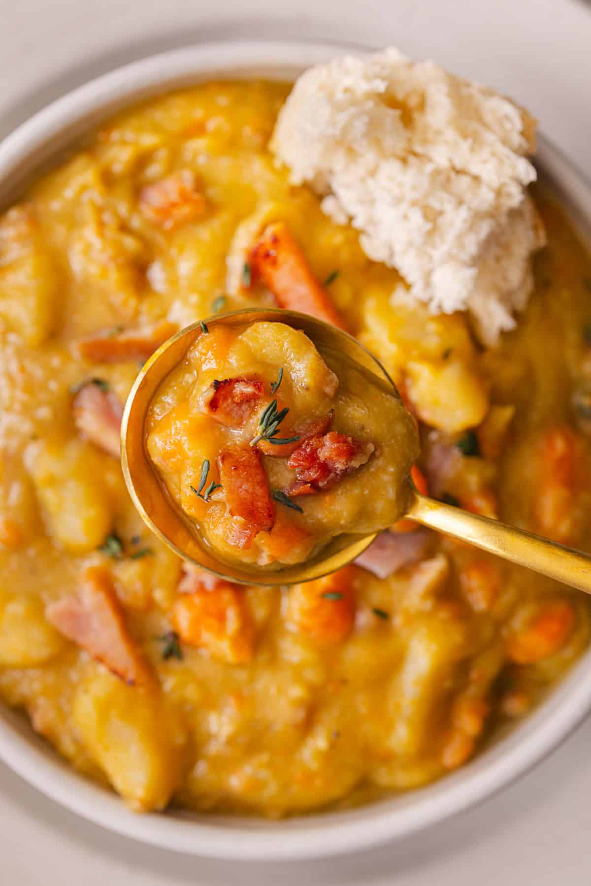 With just a handful of ingredients and minutes of prep, this Slow Cooker Split Pea Soup with Ham might be the easiest soup recipe ever. A bowl of split pea soup with ham with a piece of bread