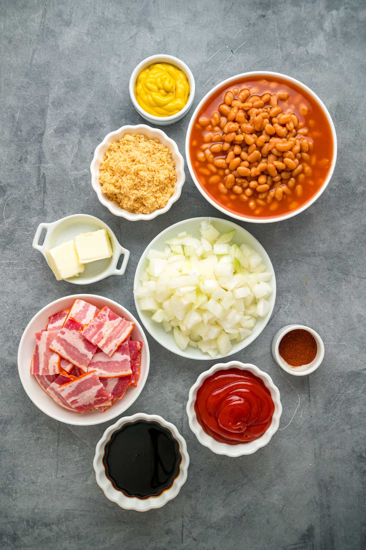 This easy Baked Beans recipe begins with pork and beans to keep things simple and salty bacon to add a final touch. Great for BBQs! Overhead view of ingredients needed to make baked beans