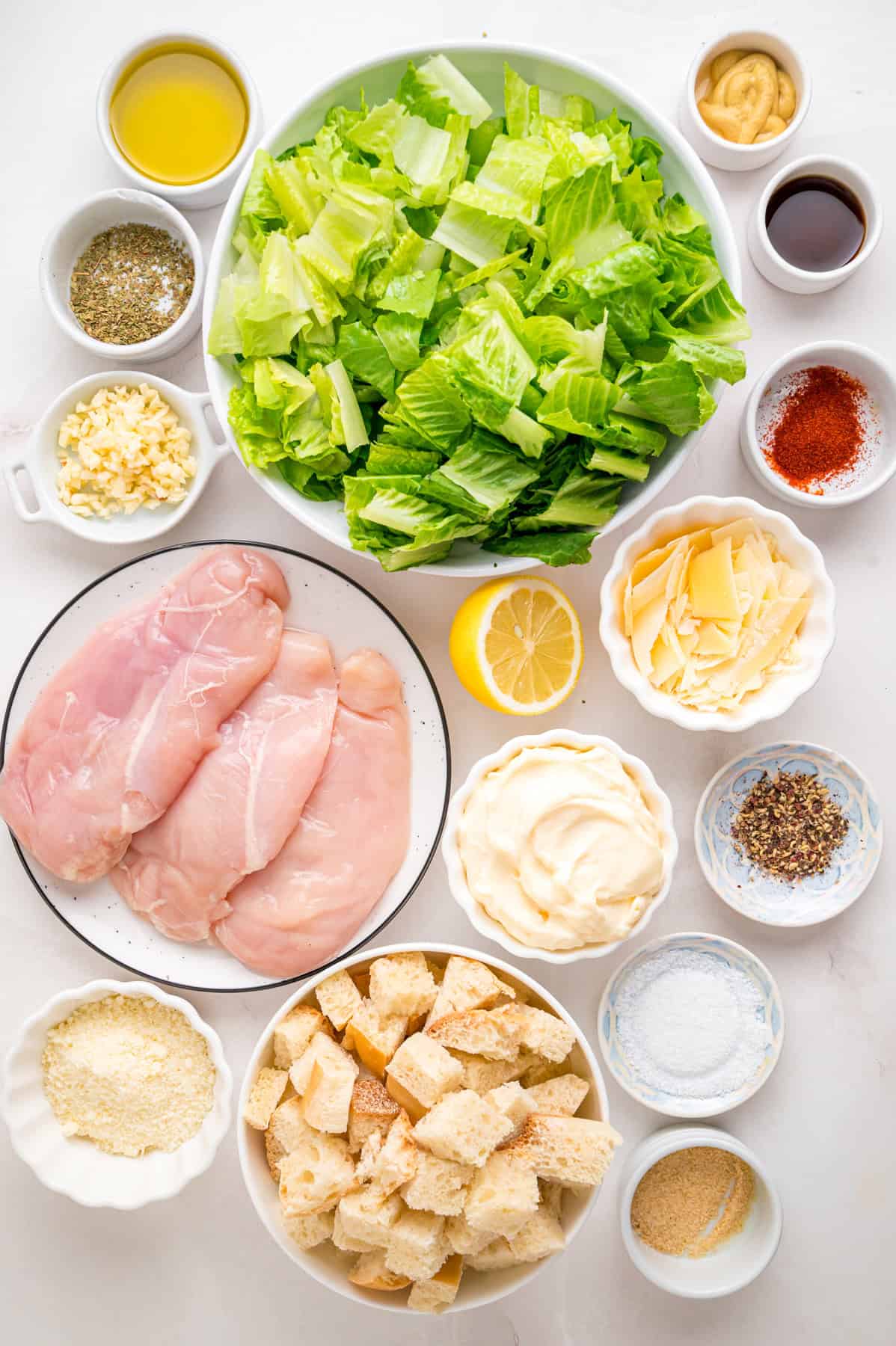 Crunchy seasoned croutons, creamy homemade dressing, and grilled strips of chicken make this Chicken Caesar Salad an easy dinner. Overhead view of ingredients needed to make chicken caesar salad