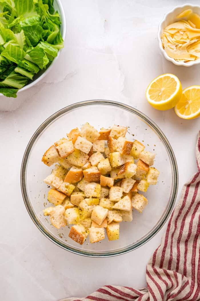 Crunchy seasoned croutons, creamy homemade dressing, and grilled strips of chicken make this Chicken Caesar Salad an easy dinner. Cubed bread and spices in a bowl