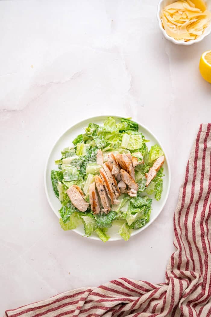 Crunchy seasoned croutons, creamy homemade dressing, and grilled strips of chicken make this Chicken Caesar Salad an easy dinner. Strips of chicken on a bed of romaine lettuce