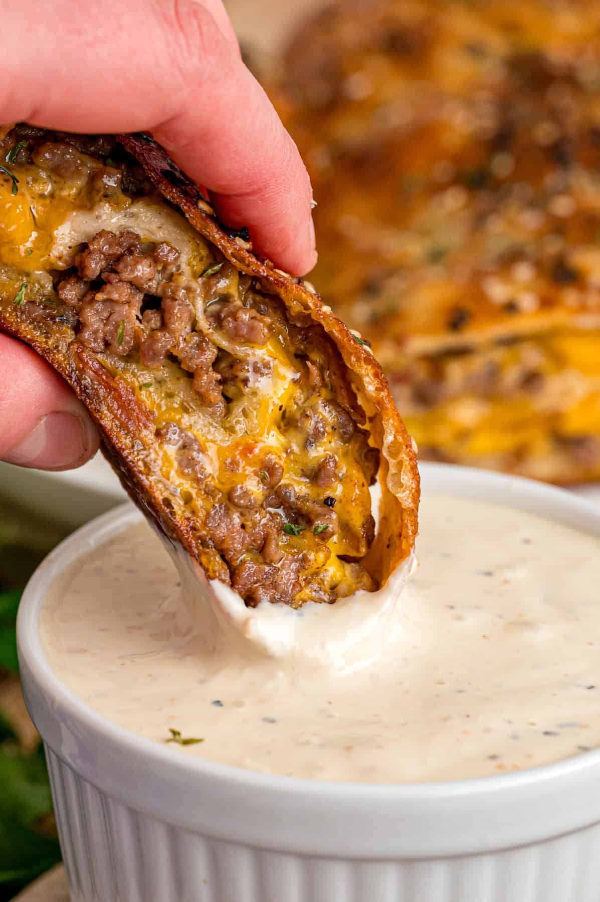 A hand dipping a slice of garbage bread into dip