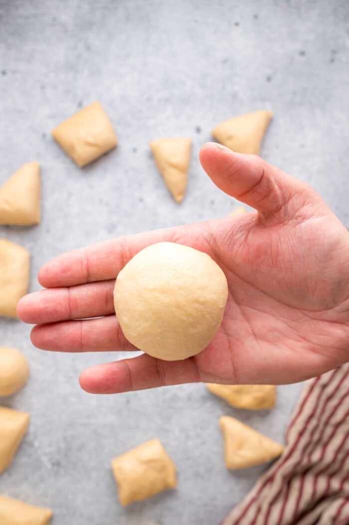 This Hawaiian Rolls recipe makes soft, fluffy rolls that taste just like the store-bought version – maybe even better. A hand holding a small ball of dough