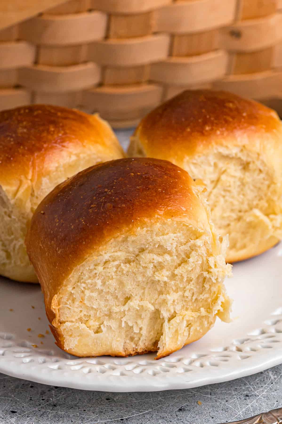 This Hawaiian Rolls recipe makes soft, fluffy rolls that taste just like the store-bought version – maybe even better. Three homemade Hawaiian rolls on a white plate