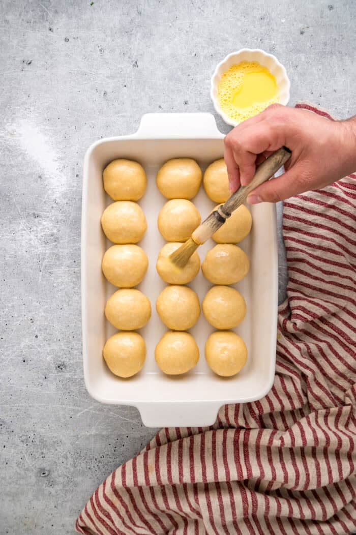 This Hawaiian Rolls recipe makes soft, fluffy rolls that taste just like the store-bought version – maybe even better. Brushing balls of dough with egg wash