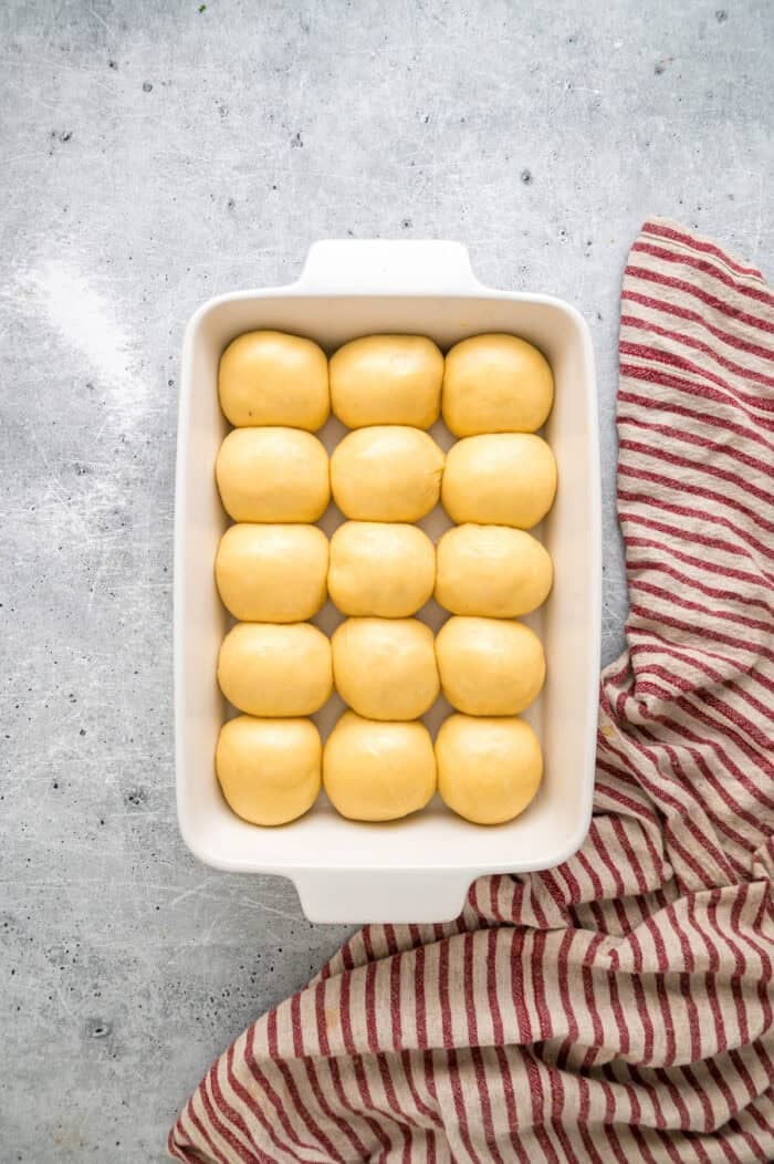 This Hawaiian Rolls recipe makes soft, fluffy rolls that taste just like the store-bought version – maybe even better. Balls of dough in a baking dish after rising