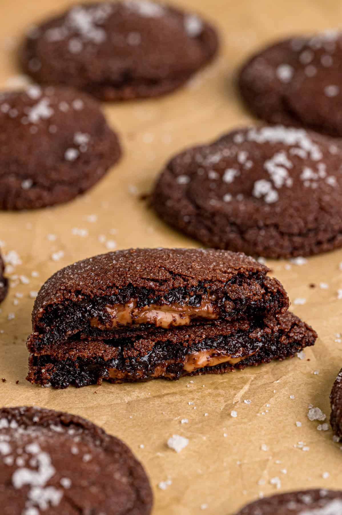 Rolo cookies on a baking sheet, one cut in half to show the caramel inside