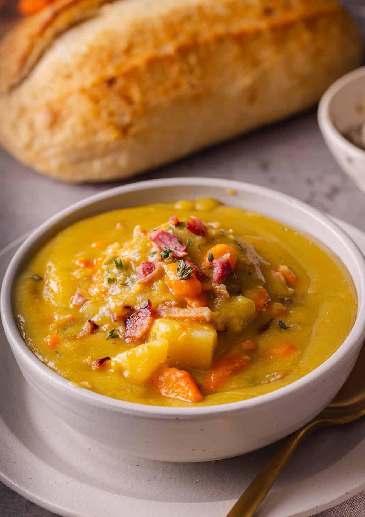 With just a handful of ingredients and minutes of prep, this Slow Cooker Split Pea Soup with Ham might be the easiest soup recipe ever. Split Pea Soup in a bowl served with crusty bread