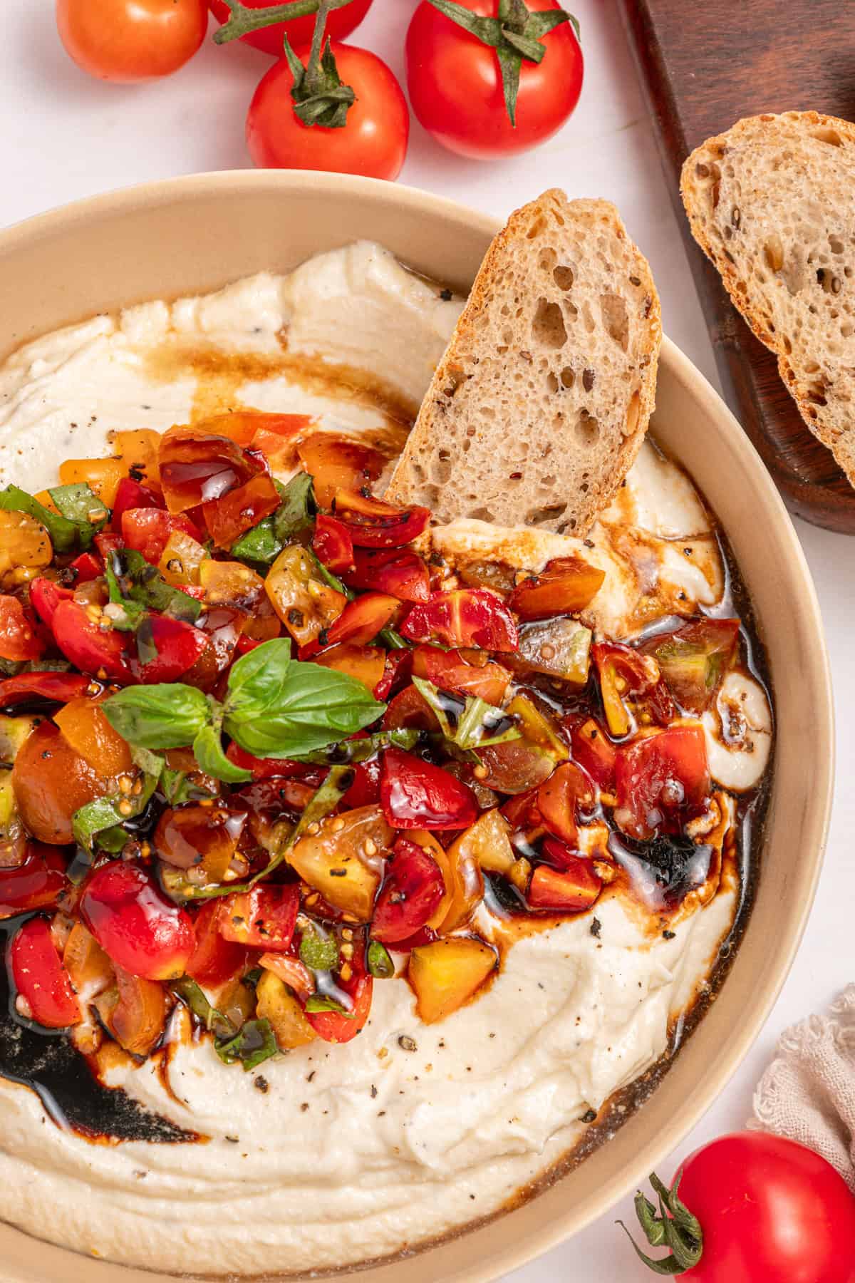 A bowl of bruschetta dip with a crostini in the bowl