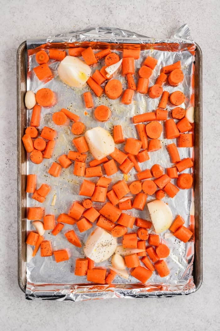 With caramelized carrots, onion, and garlic, this Roasted Carrot Soup is ready in 45 minutes. Gluten-free & vegetarian! Chunks of carrot, onion, and garlic on a baking sheet