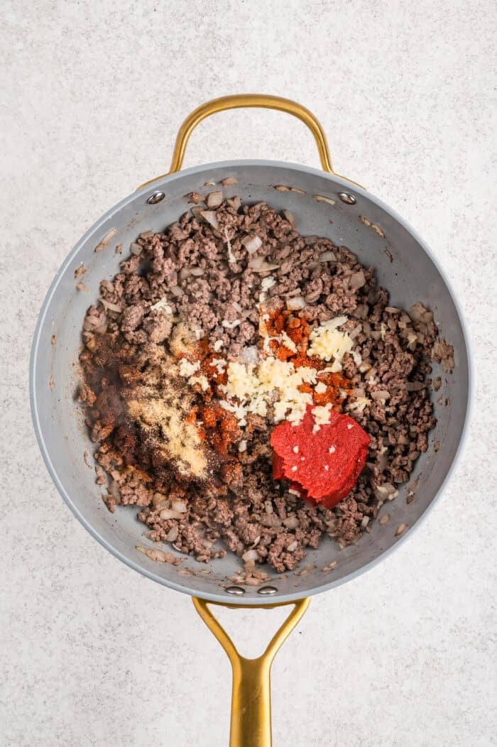 Spices, flour, and tomato paste added to cooked ground beef