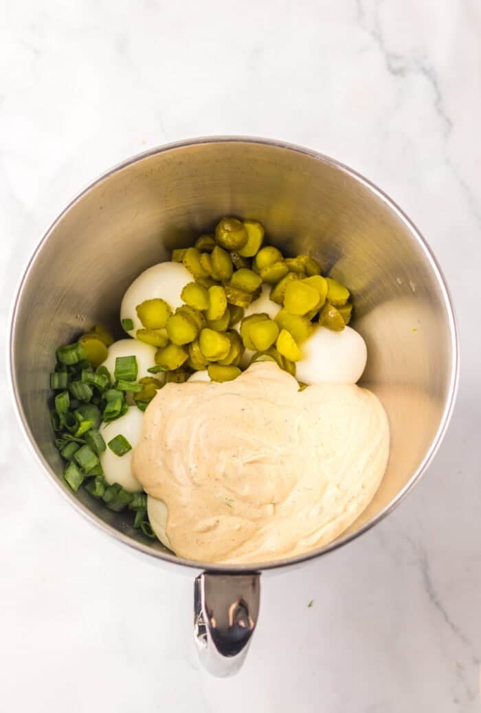 Eggs, dill pickles, scallions, and dressing in a mixing bowl