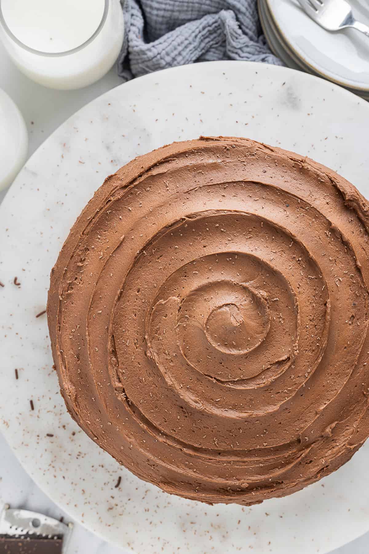 Chocolate and vanilla cake batter are swirled together, baked, and then layered with chocolate buttercream to create this Marble Cake recipe. Overhead view of swirled chocolate buttercream on a cake