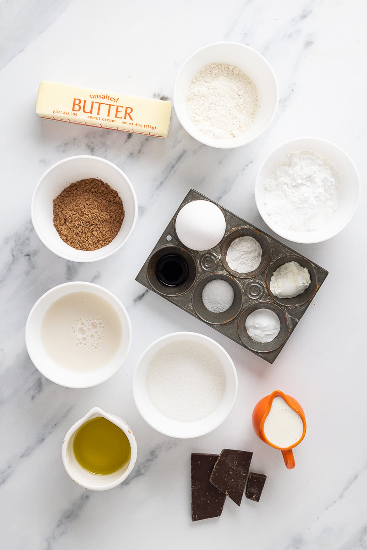 Chocolate and vanilla cake batter are swirled together, baked, and then layered with chocolate buttercream to create this Marble Cake recipe. Overhead view of ingredients needed to make marble cake